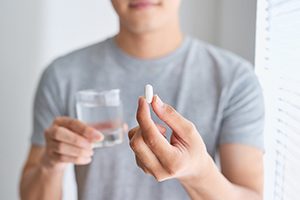 Closeup of patient holding oral conscious sedation medication and a glass of water