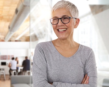 An older woman smiling with her arms crossed