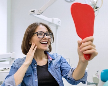 A middle-aged woman looking at her smile in the mirror