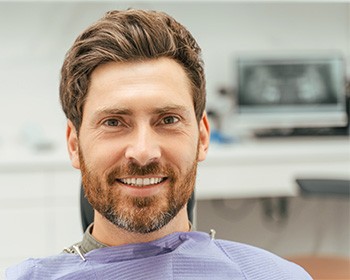Bearded man in treatment chair after oral cancer screening in Worcester, MA