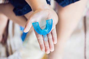 Outstretched hand holding a custom mouthguard for dental implants in Worcester
