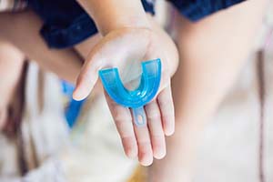 Outstretched hand holding a custom mouthguard for dental implants in Worcester