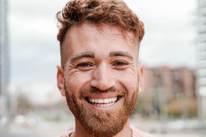 Close-up of bearded man smiling in streets of city