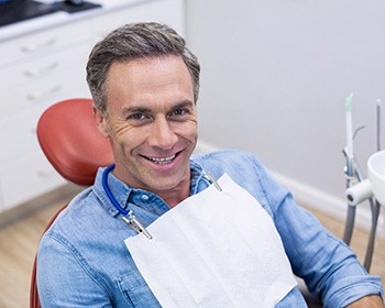 Senior man sitting in chair smiling and waiting for periodontist