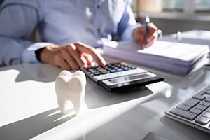 Dental tools on $100 bills representing the cost of sedation dentistry in Worcester