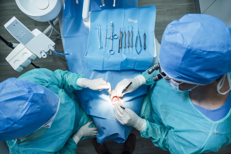two dental professionals performing a gum graft on a patient