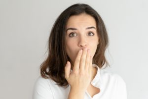 Woman covering mouth, worried because her dental implant feels loose