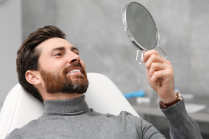Bearded man checking his smile in a mirror