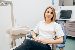 Female periodontal patient leaning back in chair and smiling