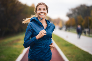 Woman in a hoodie jogging on a cloudy day