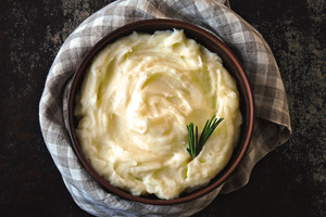 Wooden bowl of mashed potatoes with a garnish
