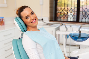 Smiling female patient in treatment chair at periodontist’s office