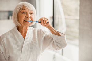 Senior woman brushing her teeth with a blue toothbrush